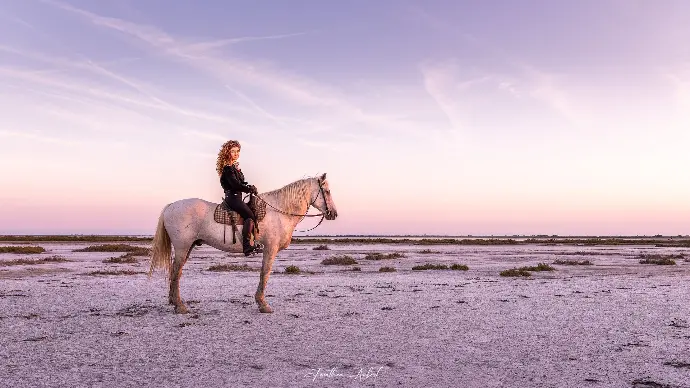 Cavalière posant sur un cheval camarguais dans un paysage naturel au crépuscule, photographie par Jonathan Aubert pour La Fadaise.